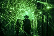 People walk through a hall of mirrors lit only by many reflected beams of green lasers.