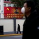 People wearing masks walk past a portrait of Chinese President Xi Jinping.
