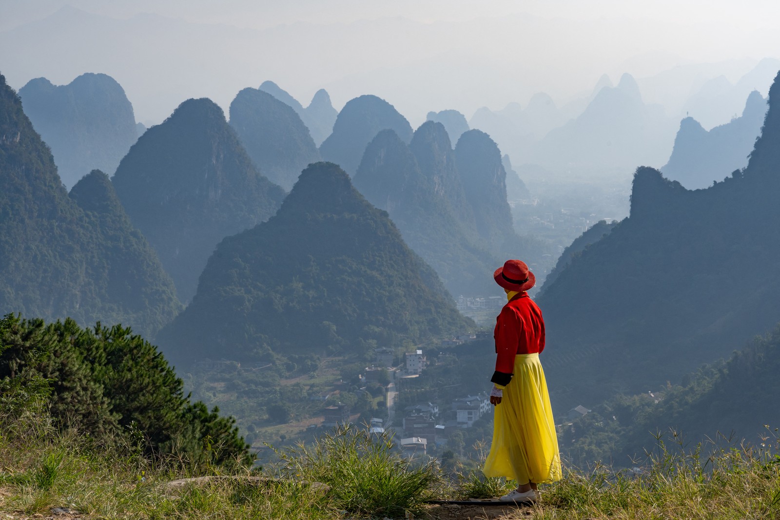 A woman looks out over a valley toward many steep hills.