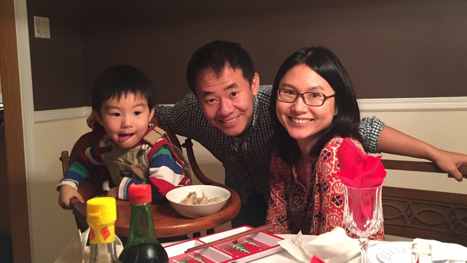 Xiyue Wang poses with his wife and young son at a dinner table.
