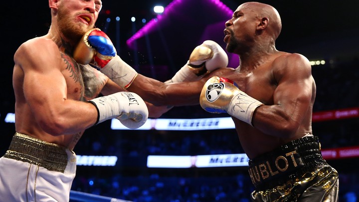 Floyd Mayweather Jr. lands a hit against Conor McGregor during a boxing match.