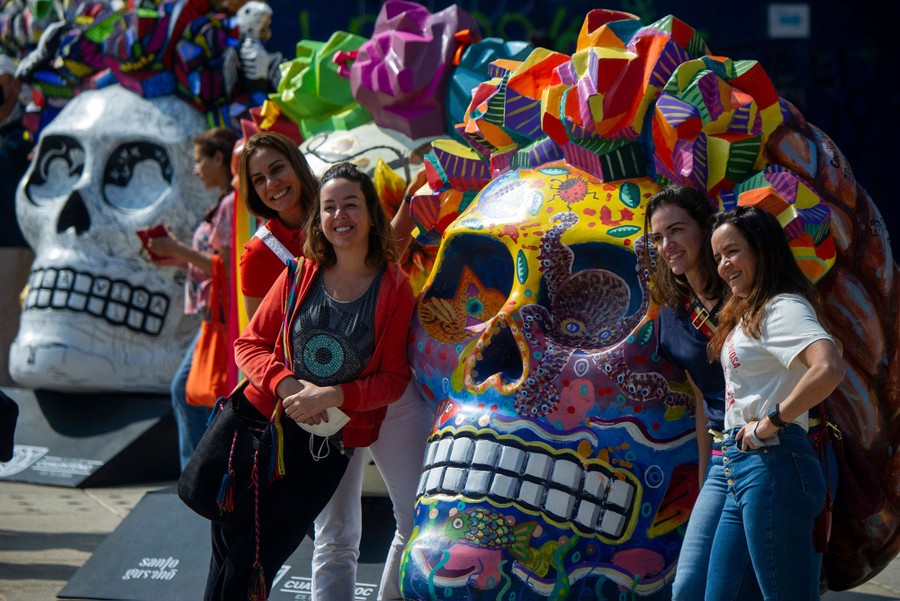 Several people pose for a photo alongside giant skull art installations.