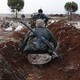 Two members of al-Qaeda's Nusra Front in Syria hold weapons while standing in a ditch.