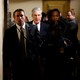 Special Counsel Robert Mueller and other officials walk down a hallway accompanied by a police officer.