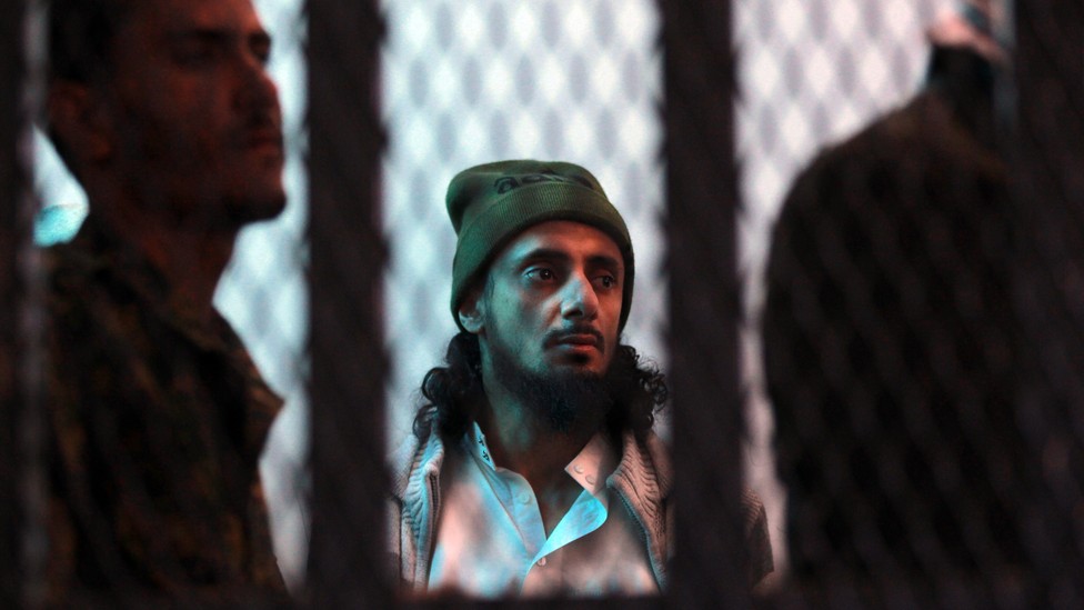 A suspected al-Qaeda militant stands behind bars.
