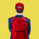 Illustration showing young man in a suit wearing MAGA hat and red backpack