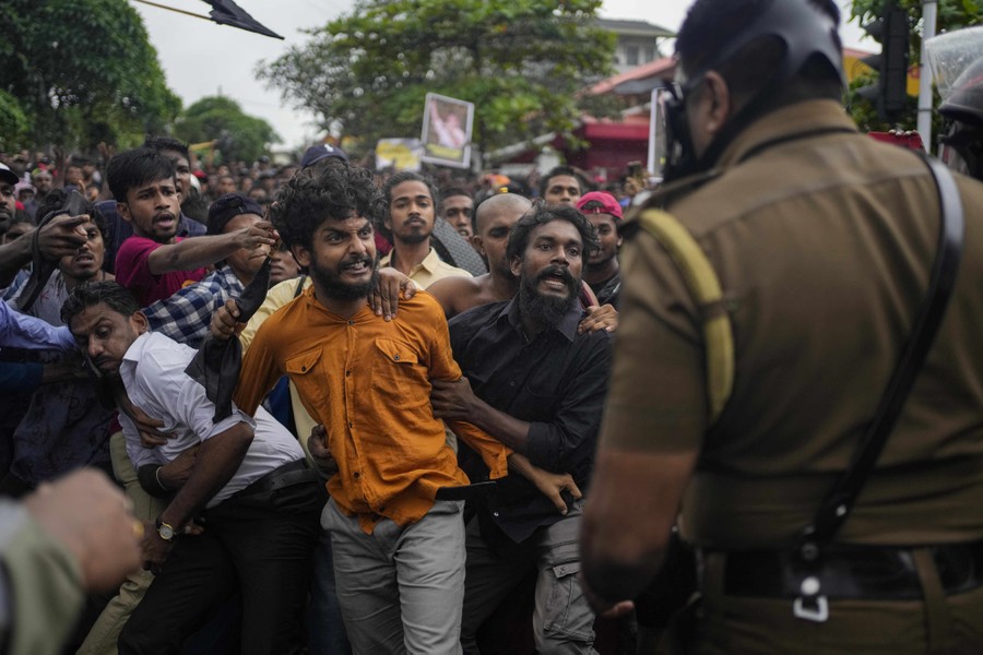 A crowd of agitated protesters faces off against police officers.