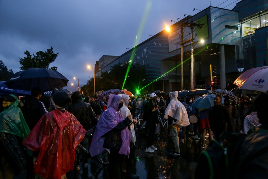 Protesters gather on a street in the rain.