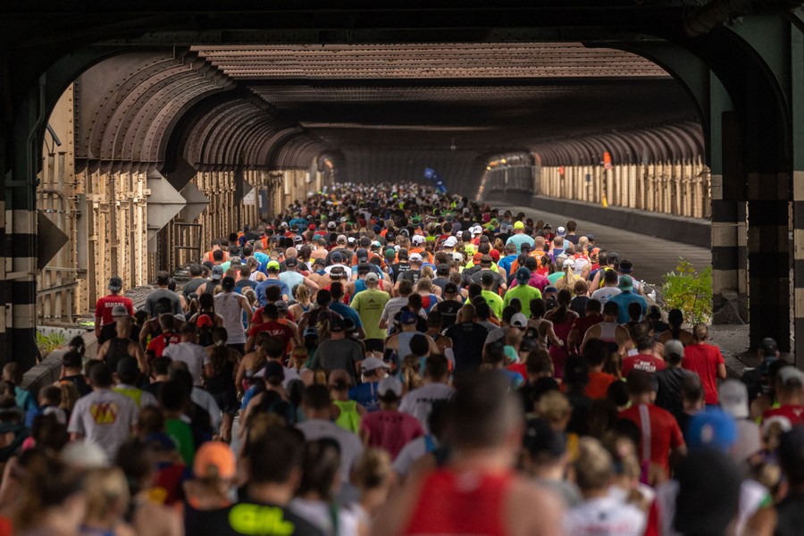A view of thousands of people running across a road bridge, captured from behind.