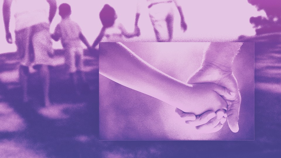 A close-up of a father holding a child's hand, set against a backdrop of a family walking together