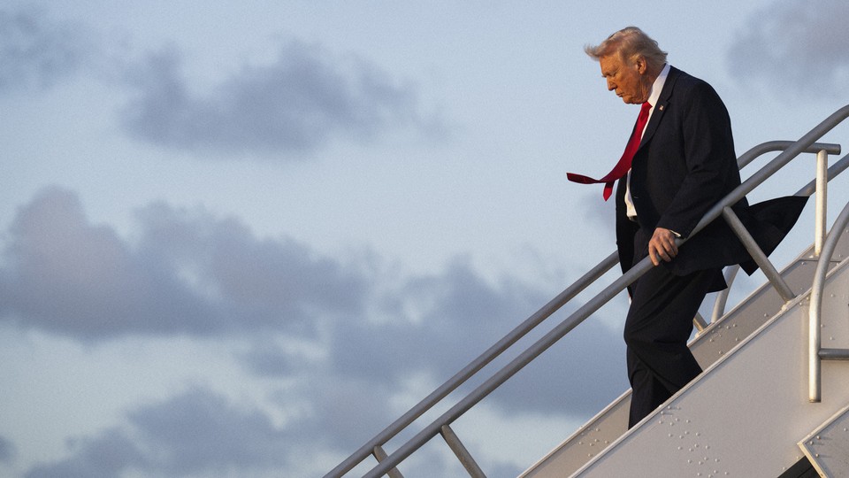 Photograph of Donald Trump walking down a staircase to exit an airplane