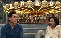 A man and a woman sitting in front of a carousel