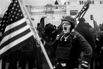 Photo of a man holding an American flag while screaming on January 6, 2021