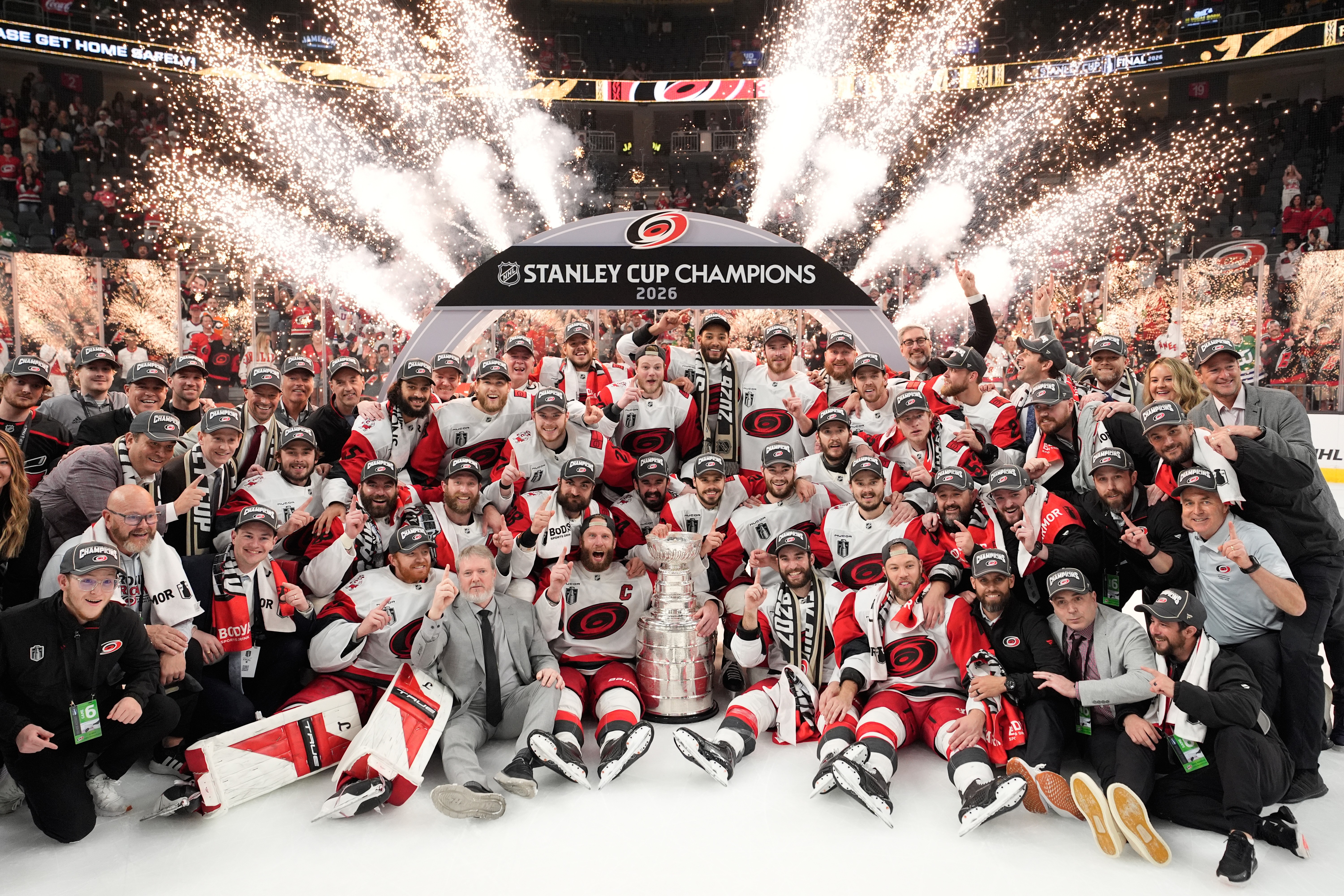 A hockey team and its coaching and support staff pose on the ice after winning the Stanley Cup.