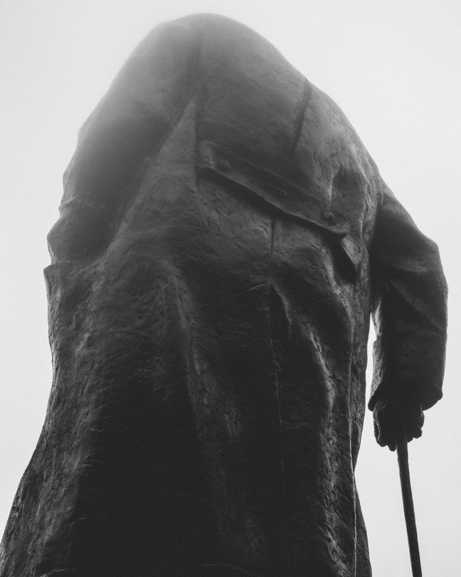 The back of a statue of a man with a cane