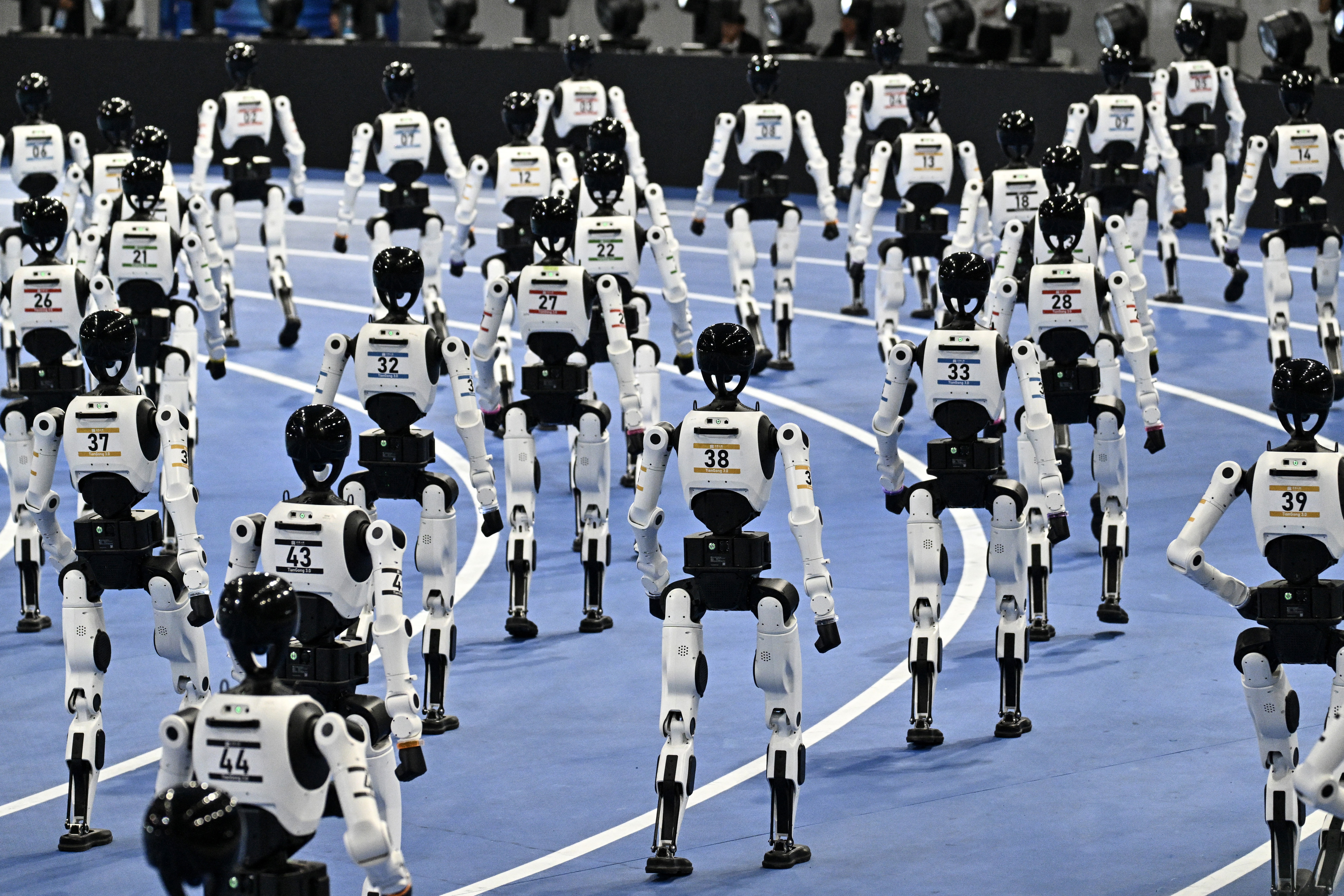 Dozens of robots parade on an indoor track.