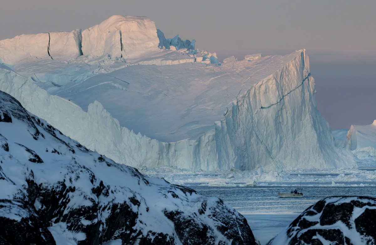 A fishing boat passes large icebergs.