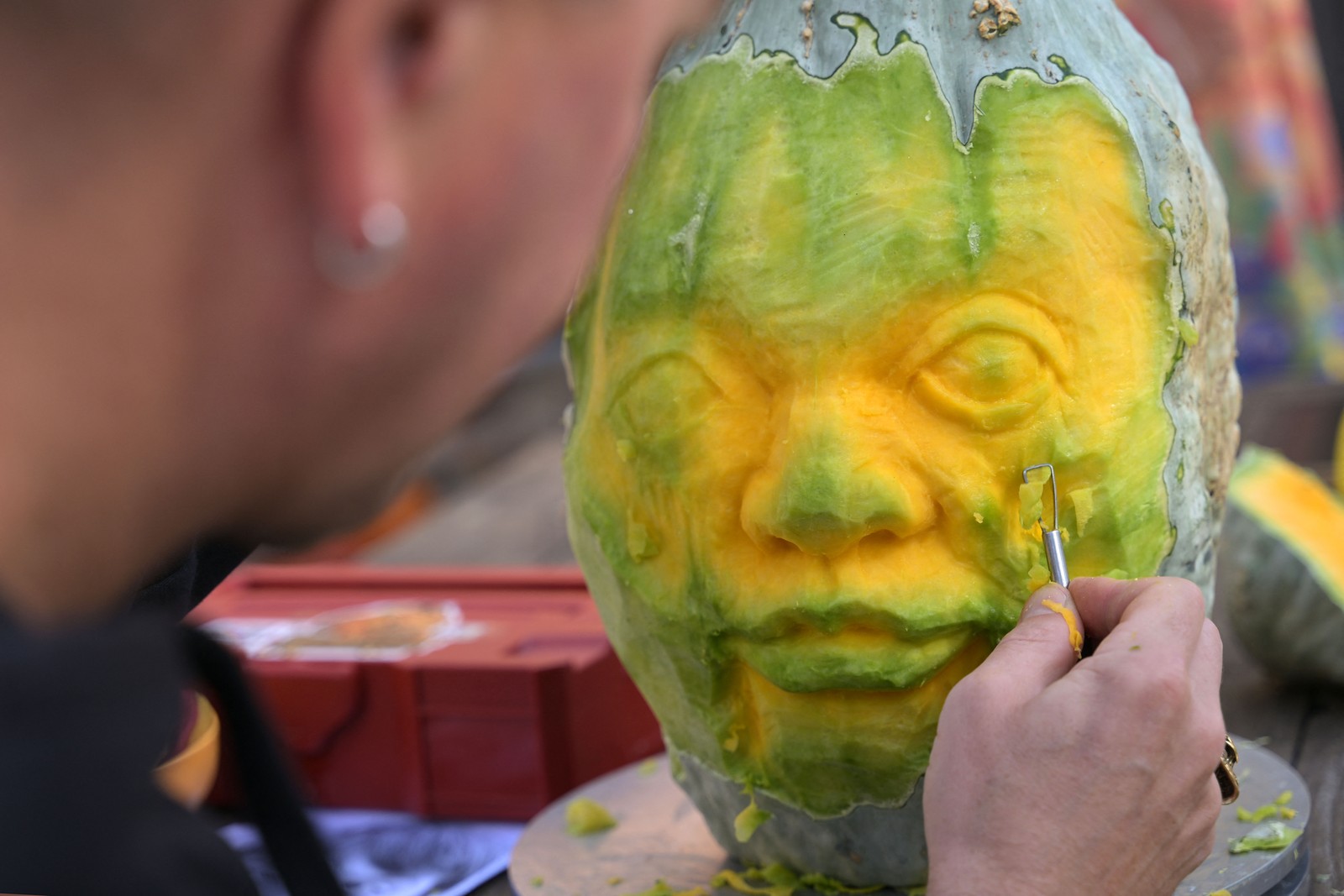 A person carves a face into a pumpkin.