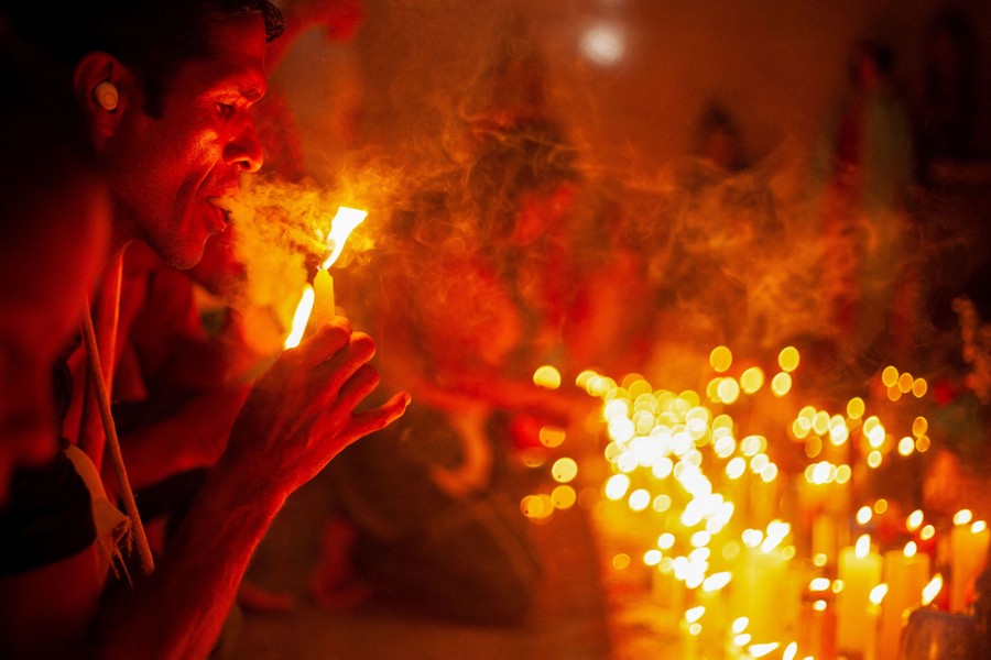 A person lights a cigar next to dozens of lit candles.