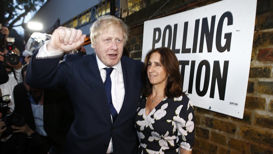 Boris Johnson raises his hand in a fist while standing with his wife outside a polling station on the day of the Brexit vote.