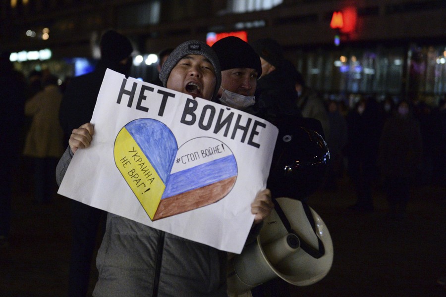 Police detain a person carrying a sign with a heart drawn on it and text (in Russian) reading "No war."