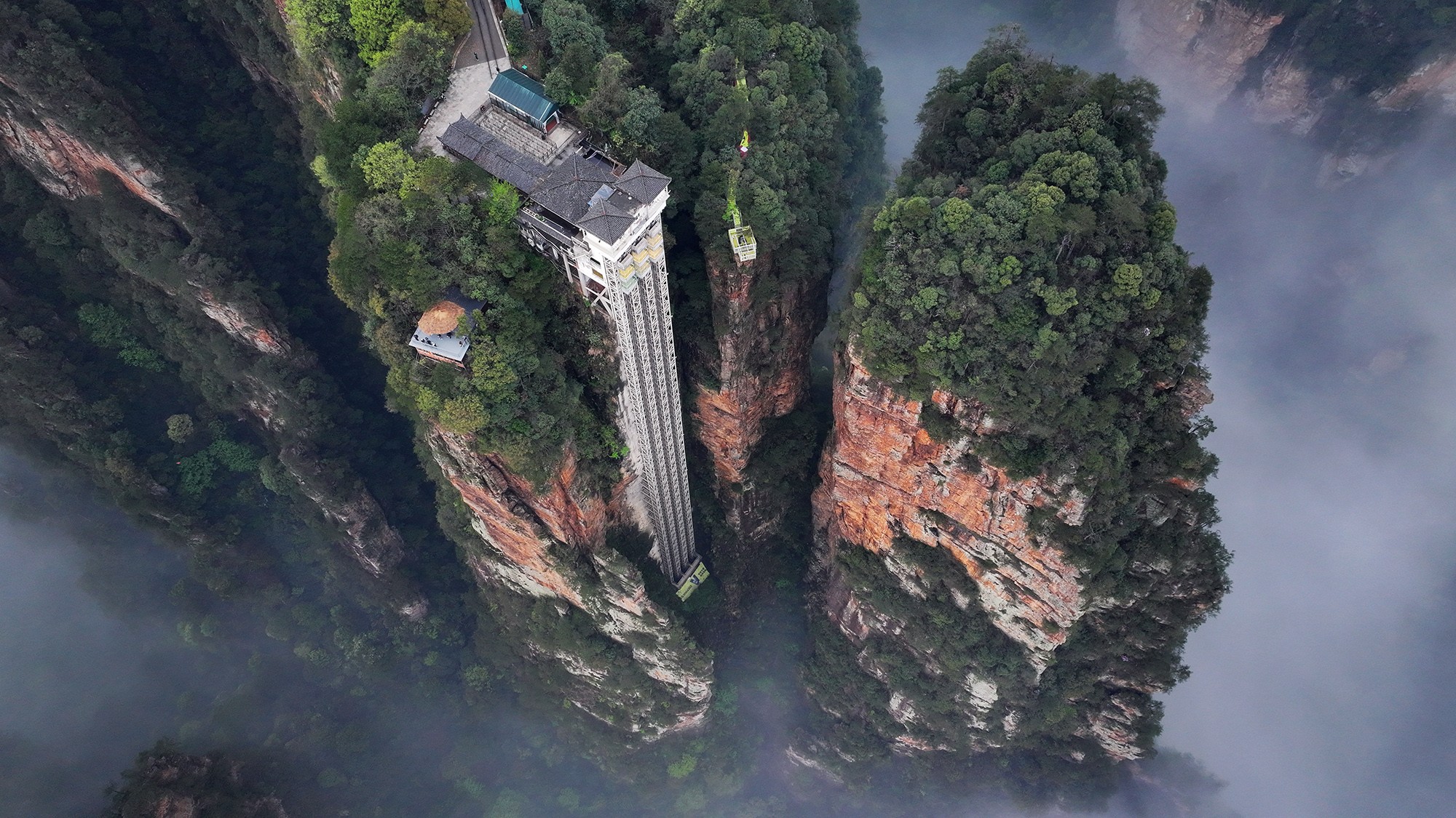 An aerial view of a very tall elevator descending into a steep-walled valley.