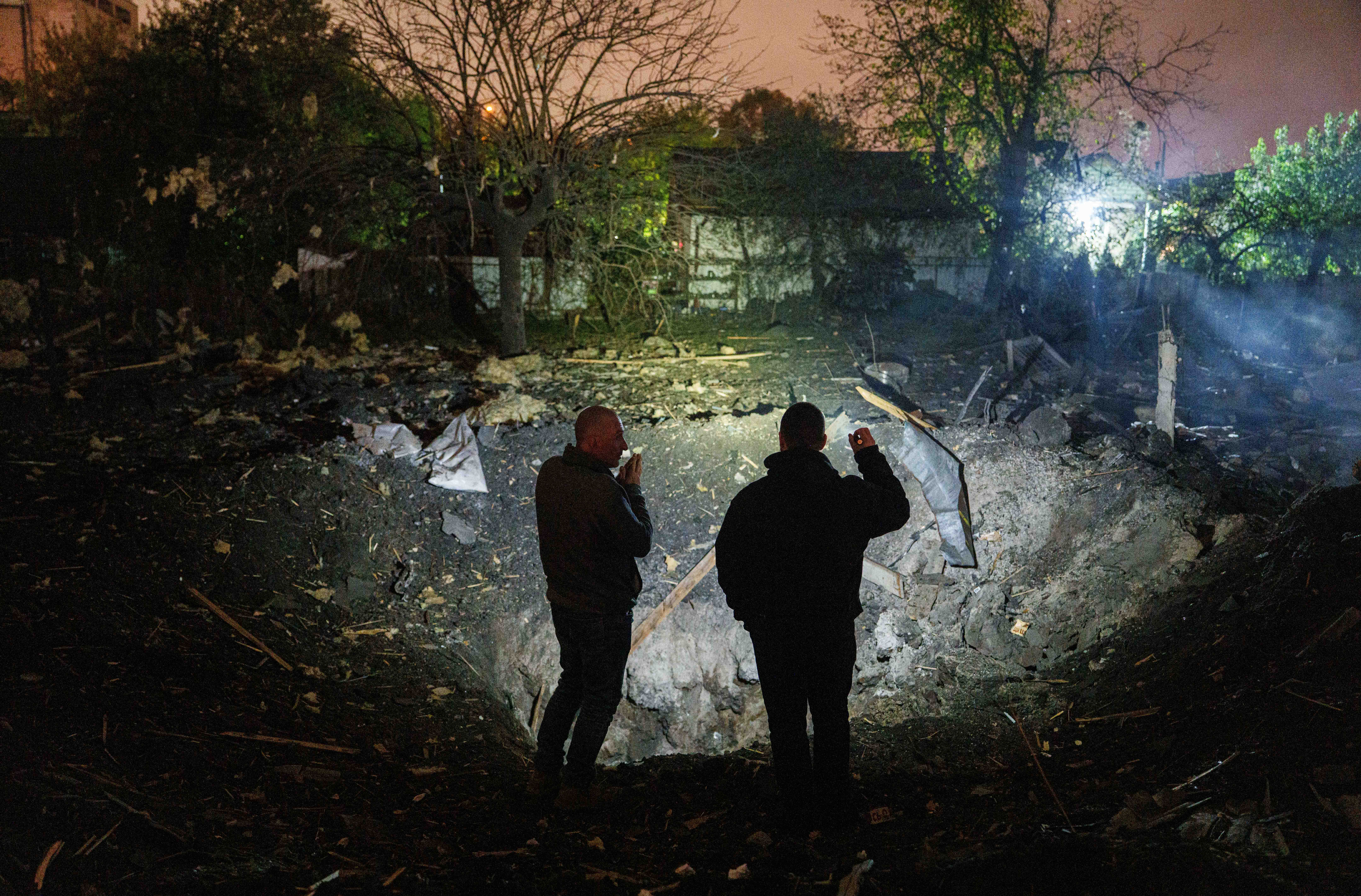Two people look at a crater after a Russian missile strike in Ukraine.