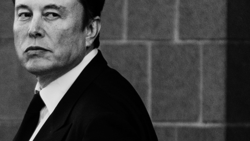 A black-and-white photo of Elon Musk in a suit and tie, looking back over his left shoulder.