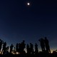 A group of people watches a solar eclipse.