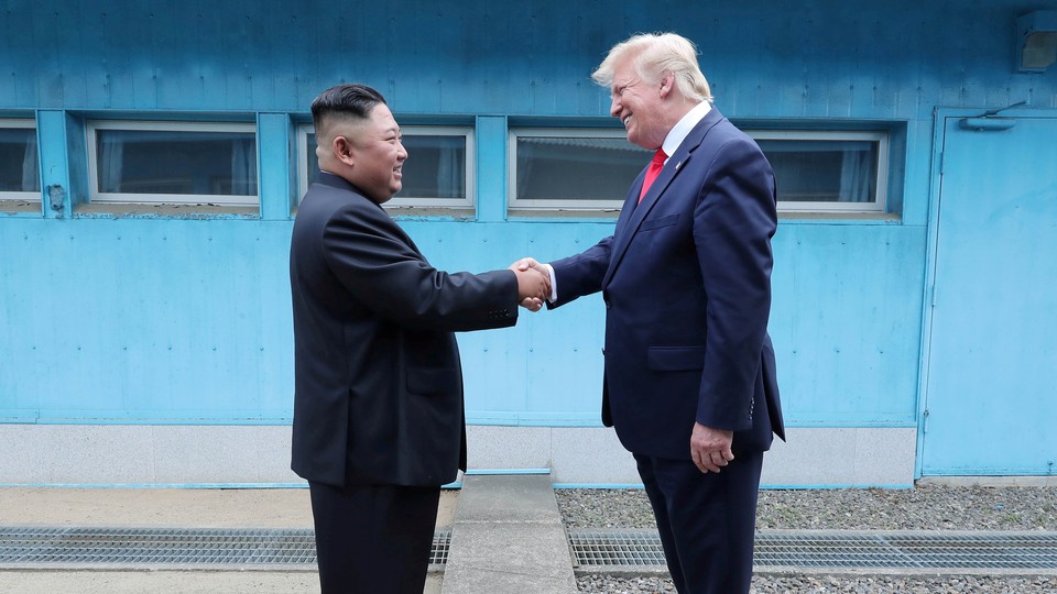 President Donald Trump shakes hands with Kim Jong Un.