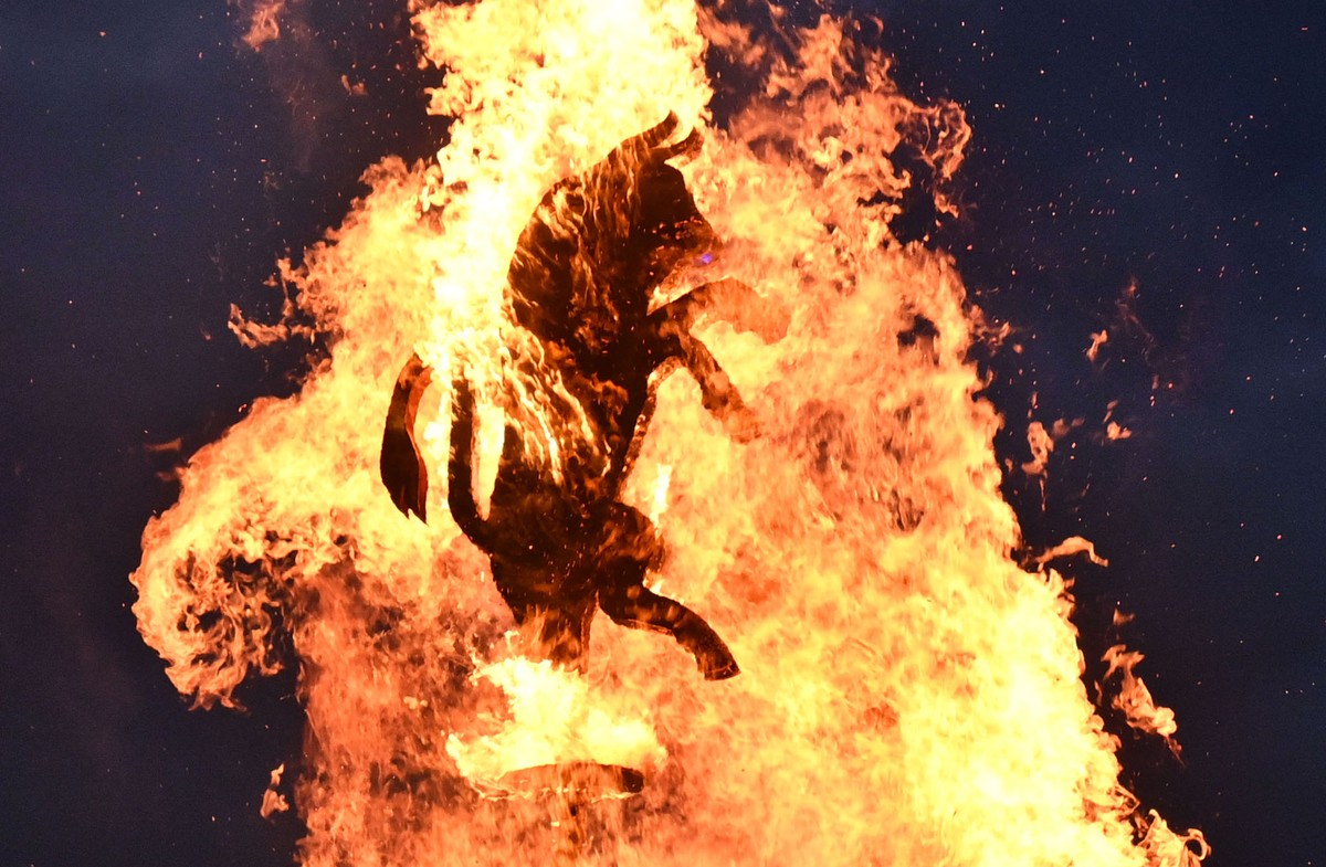 A figure of a bull is burned atop a bonfire.