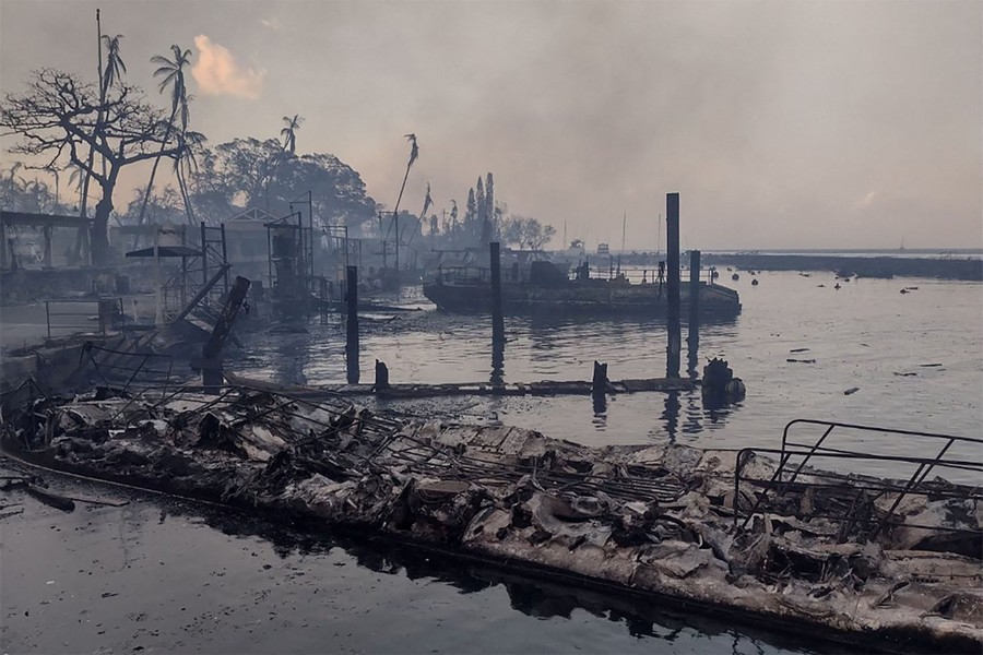 A charred boat sits along a scorched waterfront after a fire passed through.