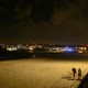 Photograph of a deserted Bondi Beach at night with two people walking on the sand
