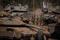 Israeli soldiers stand and walk among tanks and armored personnel carriers.