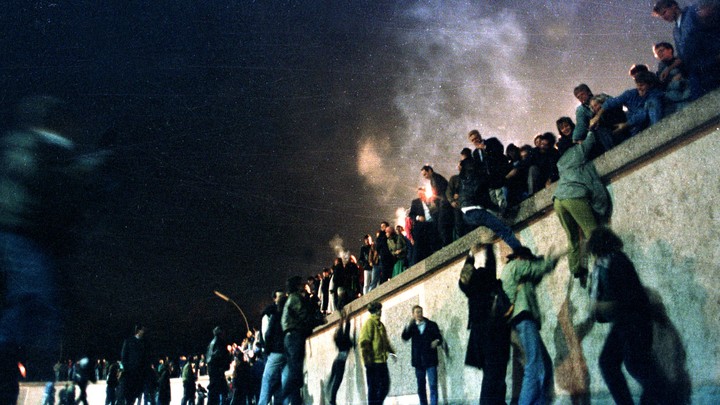 East German citizens climb over the Berlin Wall into West Berlin.