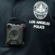 A square black camera on a police officer's black uniform shirt