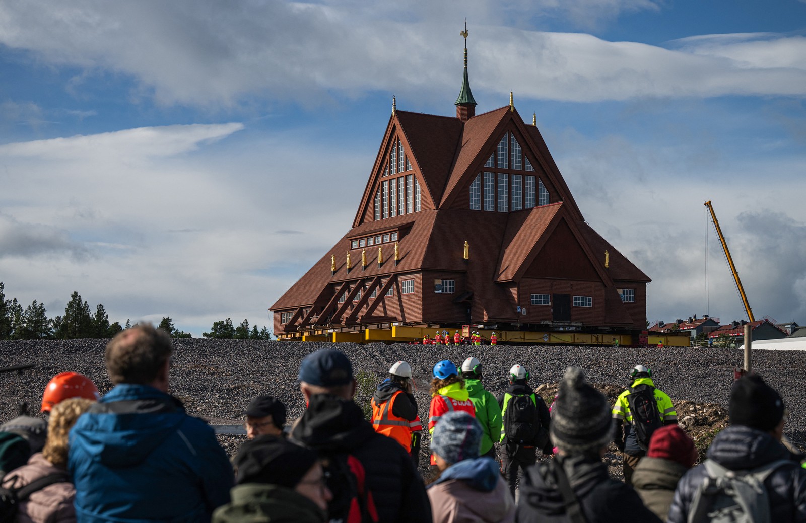 A crowd looks at a newly-repositioned wooden church.