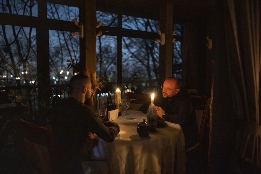 Two men dine by candlelight in a restaurant.