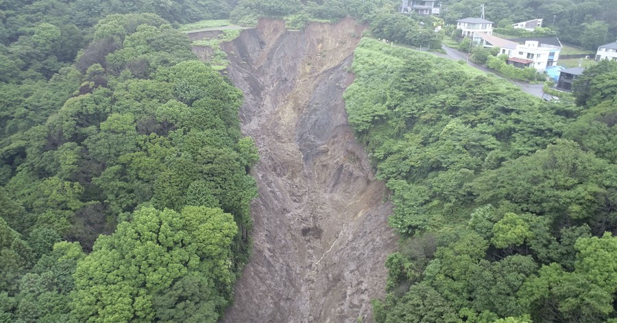 An aerial view of a large muddy cut through the land of a forested hillside.
