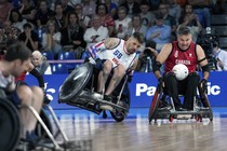 Two wheelchair rugby competitors vie for a ball during a match at the Paralympic Games.