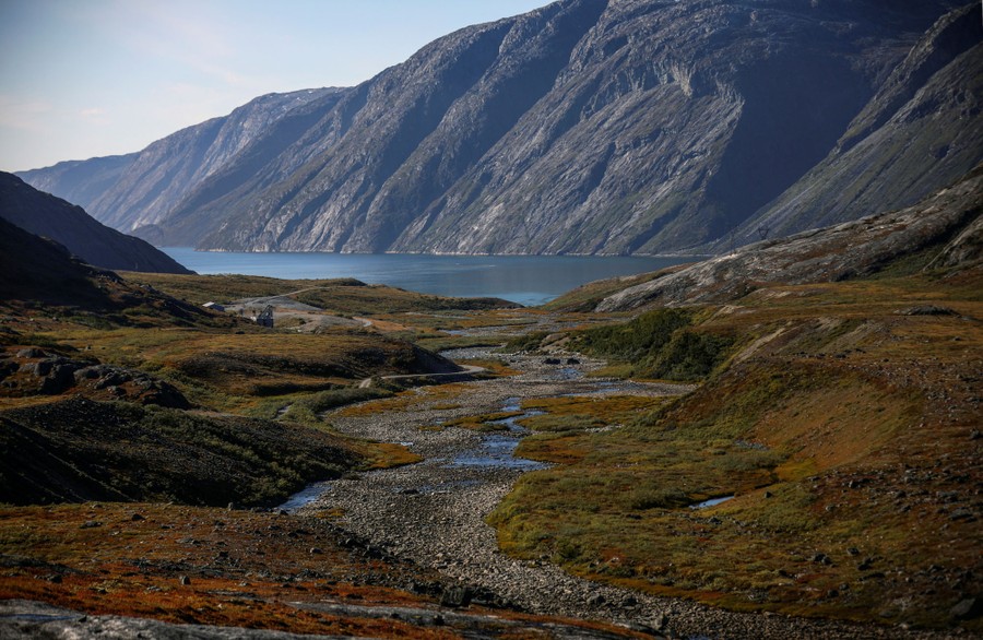 A view of a coastal mountain valley, sparsely covered in short, arctic vegetation.