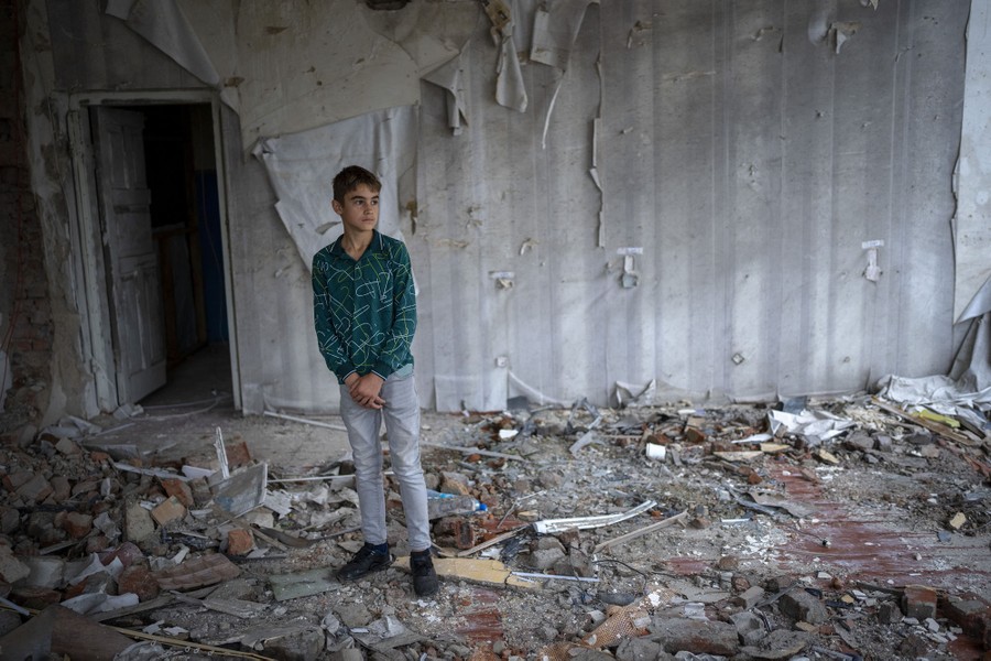 A student stands inside a ruined classroom.