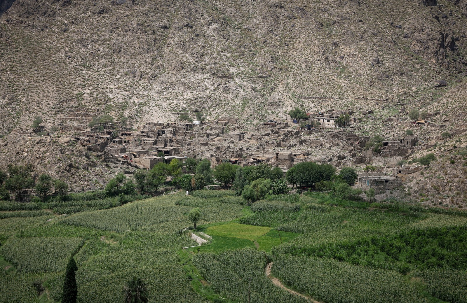 A distant view of a small mountainside village that has been badly damaged by an earthquake