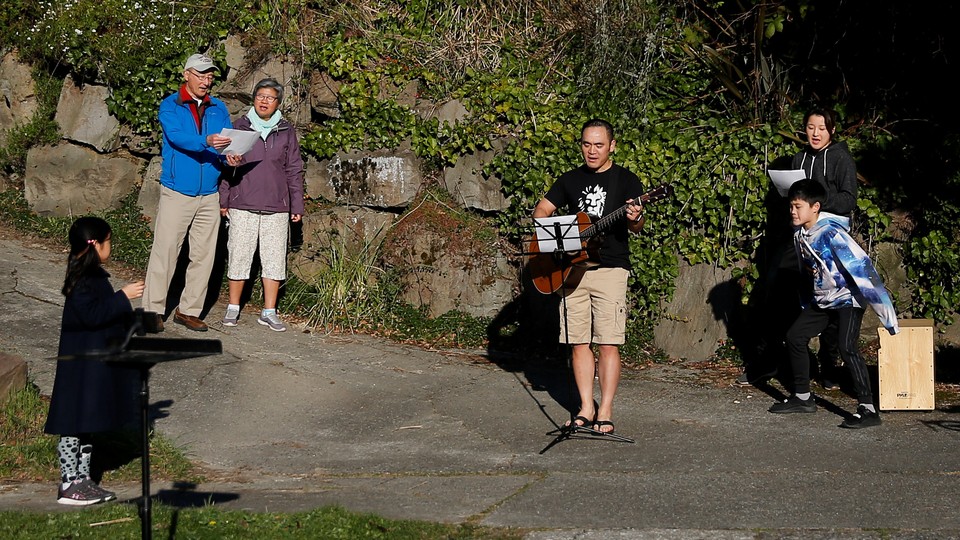 Yee Feng sings "Keep Your Head Up" by Andy Grammer with wife, Carolyn, and kids Ellie, 9, and Jediah, 11, during a neighborhood sing-along they have started doing each evening to connect with neighbors while social distancing during the coronavirus outbreak in Seattle.