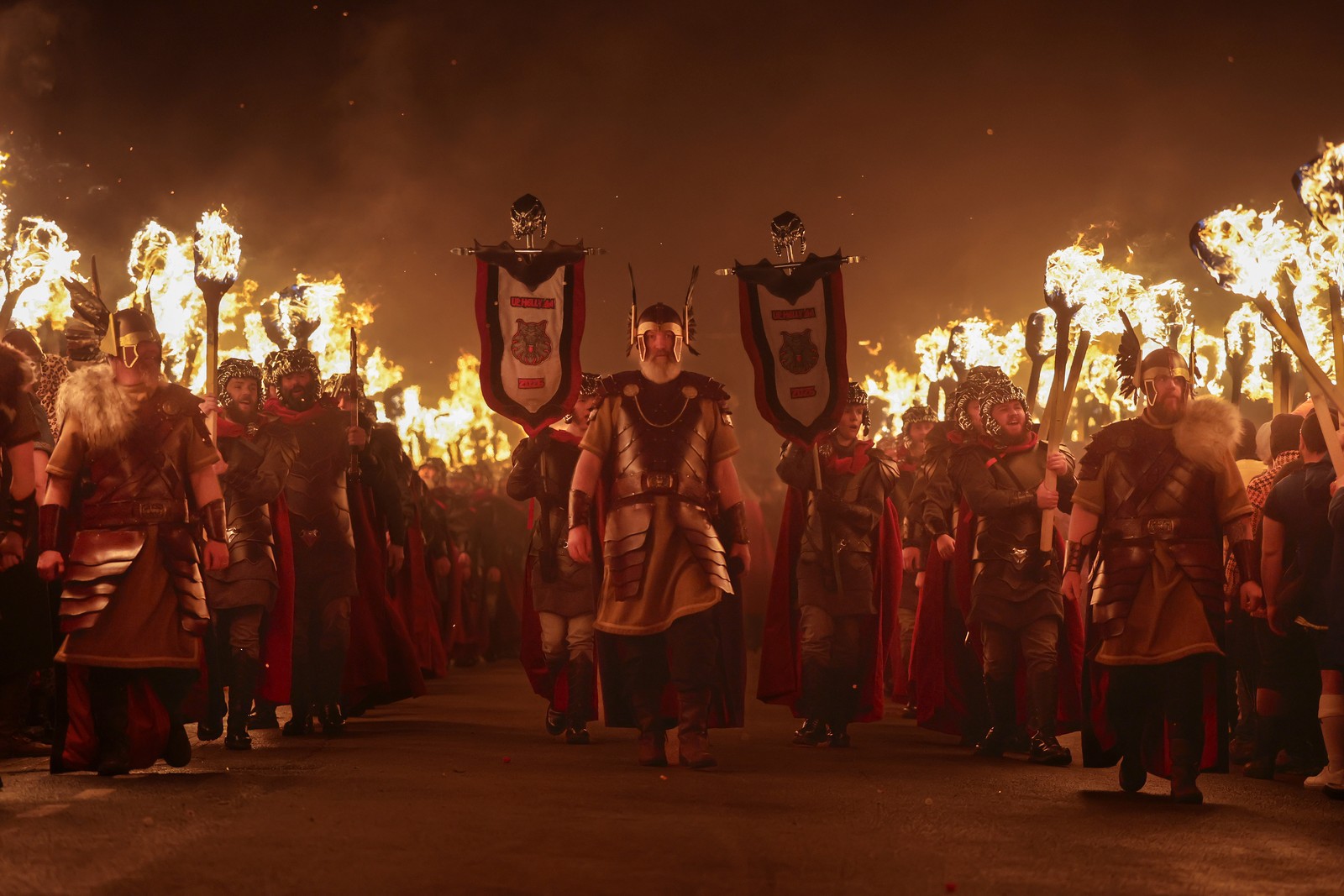 People dressed as Vikings, carrying torches, march during a parade.