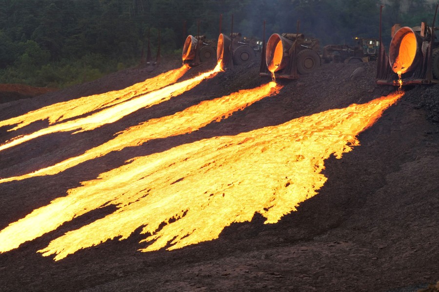 Molten slag is poured from large cauldrons onto the ground.