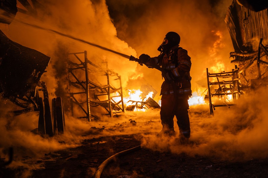 A firefighter sprays water on a large fire inside a building.