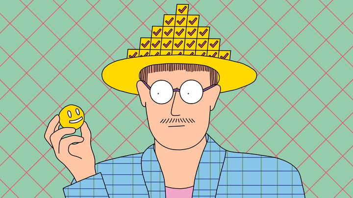 A man wearing a hat made of checkboxes and looking at a small smiley face he is holding