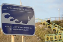 A blue tsunami warning sign on a beach