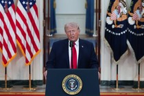 Photo of President Trump speaking at a lectern in front of flags